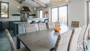 Una cocina moderna con comedor, que presenta una gran mesa de madera, sillas de mimbre y una lámpara colgante.