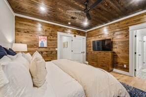 Cozy bedroom with a large bed, wooden dresser, and flat-screen TV.