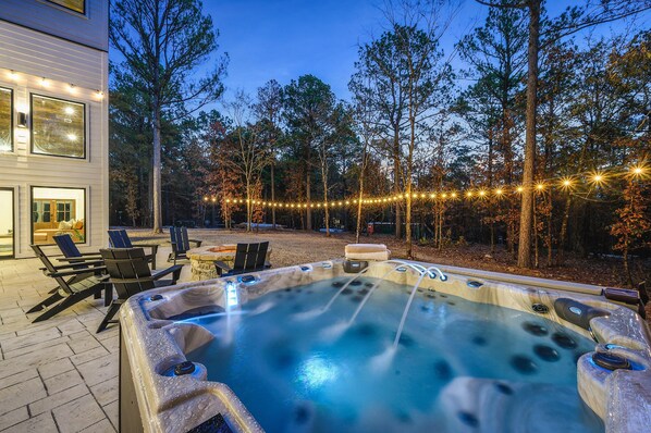 Relax in the hot tub surrounded by a patio with comfortable seating and a fire pit.