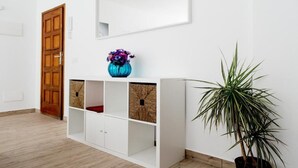 Ein Zimmer mit einer weißen Kommode, einer Holztür und einem Blumentopf.