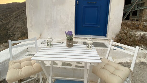 A white table with two chairs, a blue door, and a small potted plant on the table. - S&K Traditional Cycladic House Serifos (Serifos)