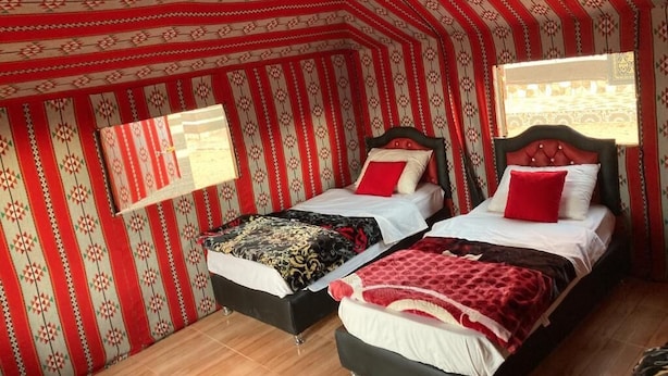 Una habitación tipo tienda de campaña con dos camas, paredes estampadas y una ventana.