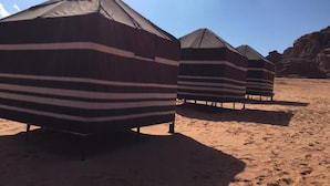Una hilera de cabañas de playa a rayas con un cielo despejado al fondo.