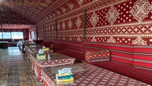 Una habitación con paredes de rojo y blanco a cuadros, un largo banco con cojines y piso de baldosas.