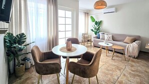 A living room with a sofa, two chairs, a coffee table, and a TV. - Rooi Santo Residence (Noord)