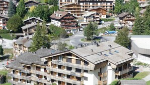 Un hotel de diversos pisos amb balcons, un telefèric al fons i una carretera en primer pla.