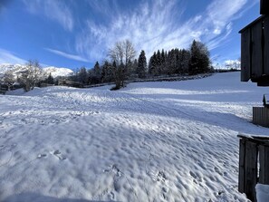 Een besneeerd landschap met een houten hut, sneeuwbedekte bomen en een heldere lucht.