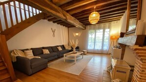 Ein gemütliches Wohnzimmer mit einem dunklen Sofa, einem weißen Couchtisch und einer hängenden Leuchte.