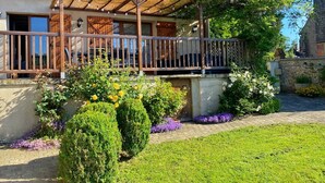 Ein Haus mit einem Holzbalkon, einem Strohdach und einem Garten mit verschiedenen Pflanzen und Blumen.
