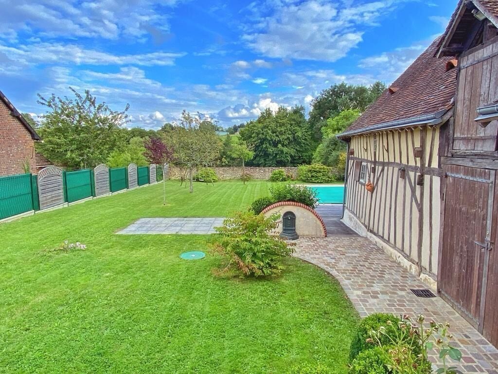 Ein gepflegter Garten mit Swimmingpool, einem Pflasterweg und einem Holzzaun.