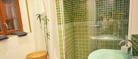 Une salle de bain avec une douche, un lavabo et une fenêtre.
