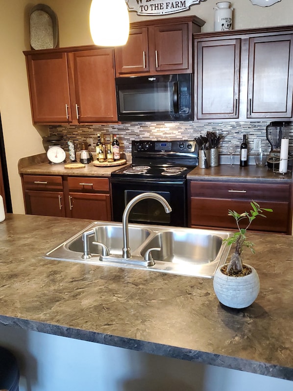 Enjoy cooking in this well-equipped kitchen with a stainless steel sink, black stove, and microwave.