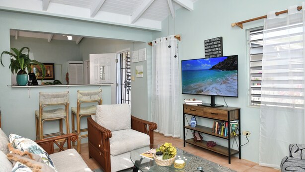 Una sala de estar con sofá, sillones, una mesa de centro, televisor y estantería.