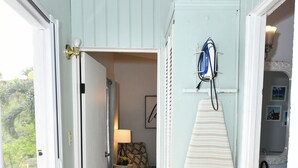 Un pasillo con un soporte para tablas de surf, una puerta que da a un cuarto con una lámpara y vistas al exterior.