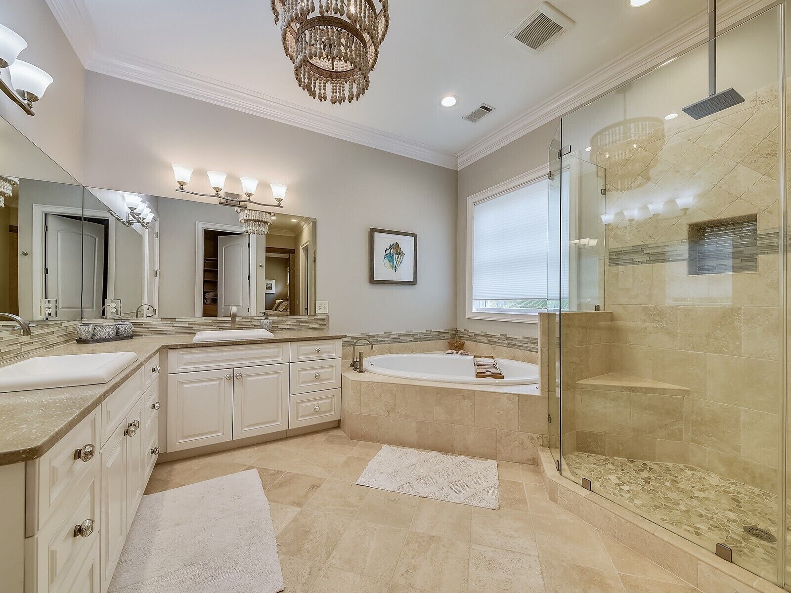 Un baño amplio con un tocador grande, una bañera independiente, ducha con mampara de cristal y un candelabro.