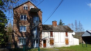 A two-story brick building with a white lower section, a metal fire escape, and a small attached structure with a satellite dish.