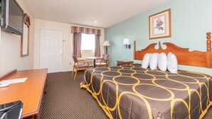 A hotel room with a large bed, a desk, a chair, a television, and a window with curtains.