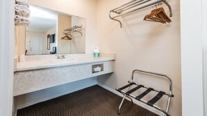 A bathroom with a sink, mirror, towel rack, and a shower chair.