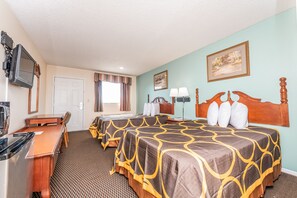 A hotel room with two beds, a desk, a television, and a window with curtains.