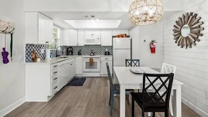Et moderne køkken med hvide skabe, en sort-hvid backsplash og en hængende lampe.