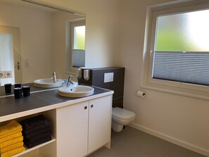 Un baño con lavabo, espejo, inodoro y ventana.