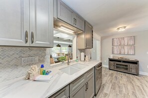 A modern kitchen with grey cabinets, a large island, and a view to the dining area.