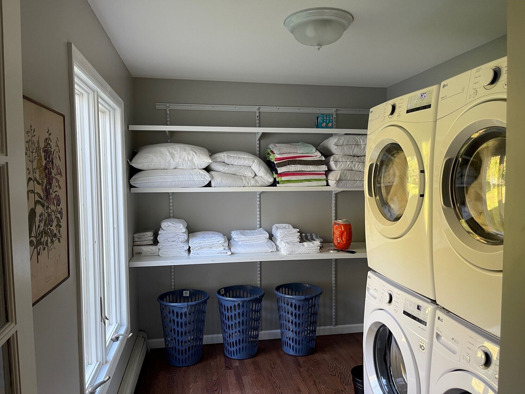 A laundry room with shelves of folded towels and laundry baskets.