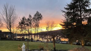 Un jardin agrémenté d’une statue, d’arbres et offrant une vue sur le coucher de soleil.