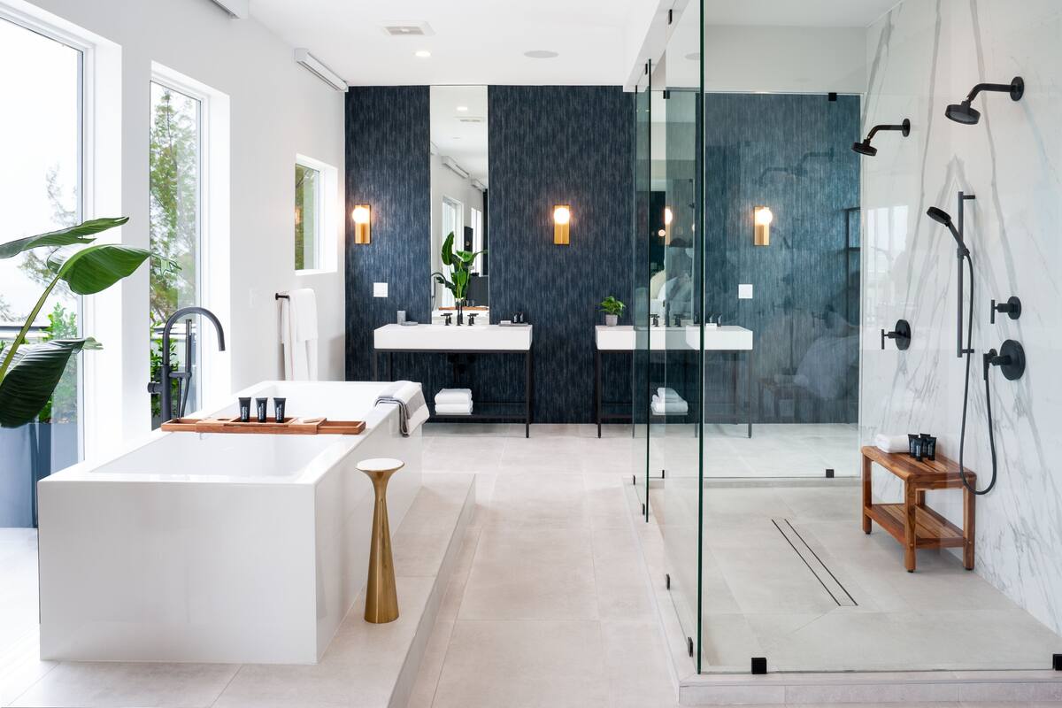 Un baño moderno con una bañera grande, dos lavamanos y una zona de ducha con paredes de vidrio.