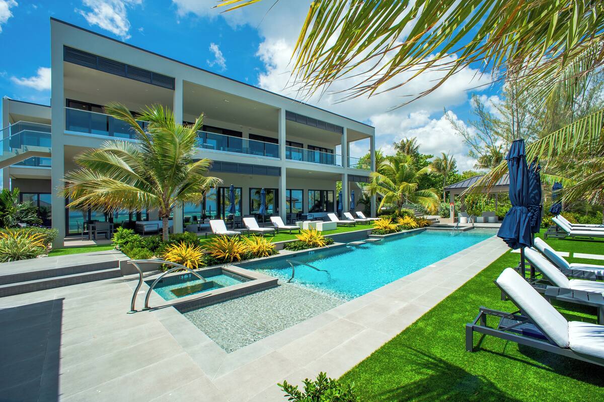 Un hotel moderno con piscina, sillones de descanso y palmeras.