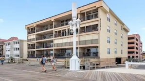 Un edificio a più piani con balconi, una passerella in legno e cielo sereno.