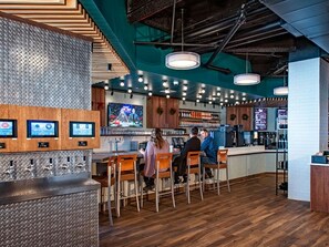 Enjoy a drink at the central bar, surrounded by comfortable seating and a digital menu display.