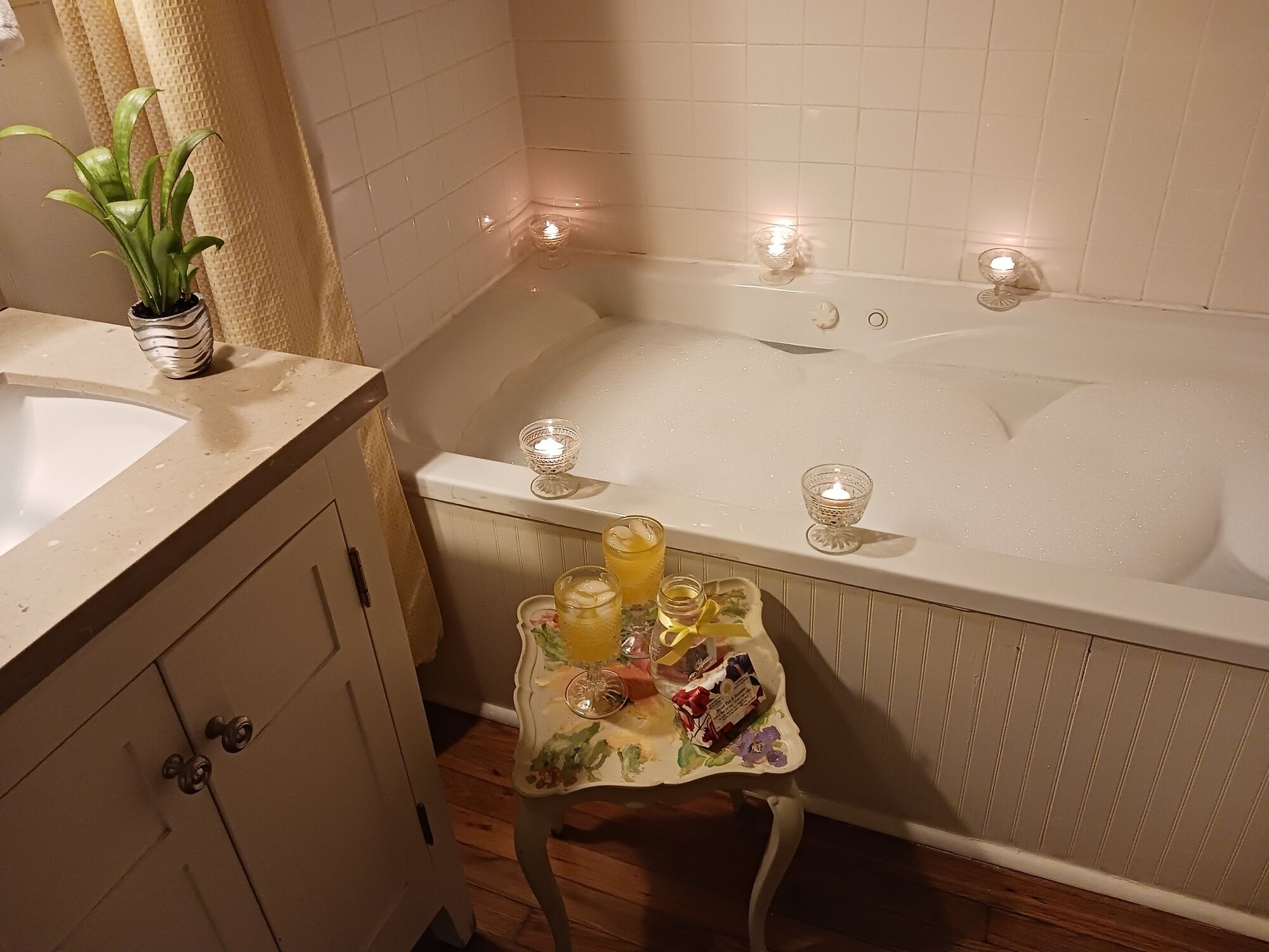 A bathroom with a bathtub, a sink, and a small table with toiletries.