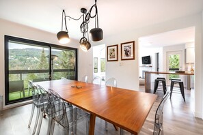 A modern dining area with a wooden table, clear chairs, and pendant lighting.
