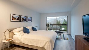 A modern bedroom with a large bed, a desk, a TV, and a window with a mountain view. - Luxury | Mountain views | Free parking | AC | BBQ (Whistler)