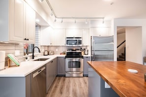 Een moderne keuken met roestvrijstalen apparatuur, witte kasten en een houten aanrecht.