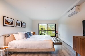 Een moderne slaapkamer met een groot bed, een bureau, een stoel en een televisietoestel.