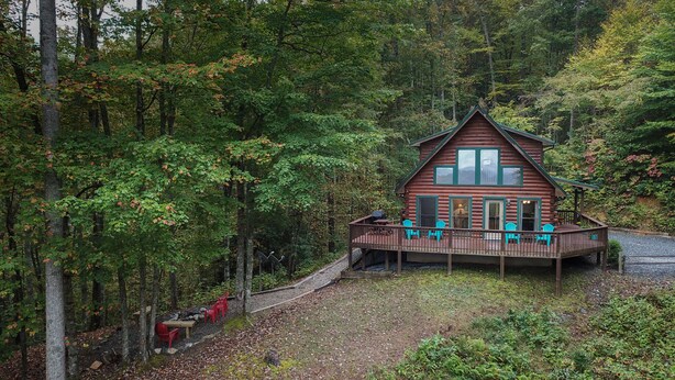 A cabin with a deck and outdoor seating area surrounded by dense forest. - Spectacular year-round views of Smokey Mountain National Park from a D-Log Cabin (Whittier)