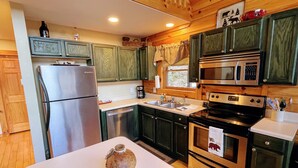 A kitchen with wooden cabinets, stainless steel appliances, and a central island. - Spectacular year-round views of Smokey Mountain National Park from a D-Log Cabin (Whittier)