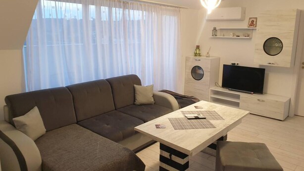 A modern living room with a sofa, a coffee table, a television, and a small cabinet. - 2-bed - Sleeps 4 - With Parking (Blagoevgrad)