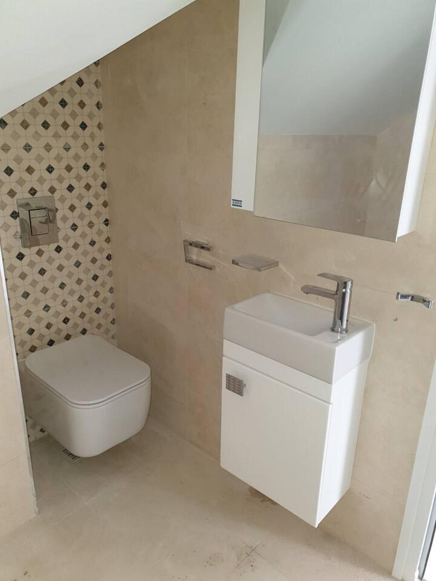 A compact bathroom with a toilet, a sink, and a mirror.