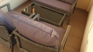 A wicker sofa with cushions and a glass coffee table in a sunlit room with a window. - 2-bed - Sleeps 4 - With Parking (Blagoevgrad)