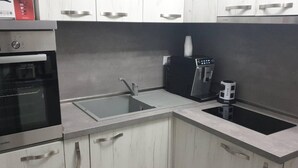 A kitchen with a built-in oven, a sink, a coffee maker, and a refrigerator. - 2-bed - Sleeps 4 - With Parking (Blagoevgrad)