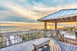 A wooden deck with a bench and a covered area overlooking a beach at sunset. - EmeraldParadiseGolfCartIncluded/Pool/WalkToBeach (Santa Rosa Beach)