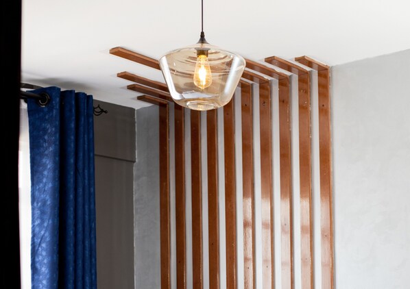 Ein Zimmer mit einer Wand aus Holzlatten, einer hängenden Leuchte und einem blauen Vorhang.