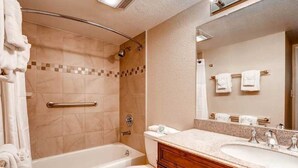 Et badeværelse med badekar, toilet og vaskebord med spejl.