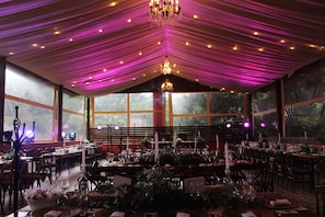 A banquet hall with tables set for a formal event, large windows, and a chandelier. - Hotel Boutique Finca de la Niebla Coatepec (Tlalnelhuayocan)