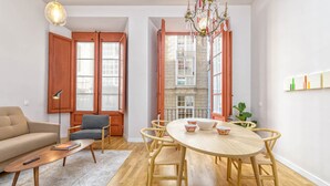 Ein modernes Wohnzimmer mit einer Couch, einem Couchtisch, einem Esstisch mit Stühlen und einer Chandelüster.