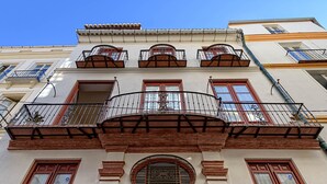 Ein Gebäude mit einem zentralen Balkon, zahlreichen Fenstern und einem Rundfenster im unteren Bereich.