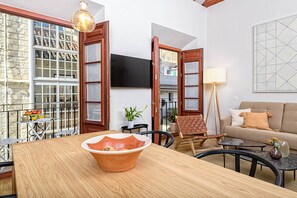 Un soggiorno con un tavolo da pranzo in legno, un divano e una TV montata a parete.